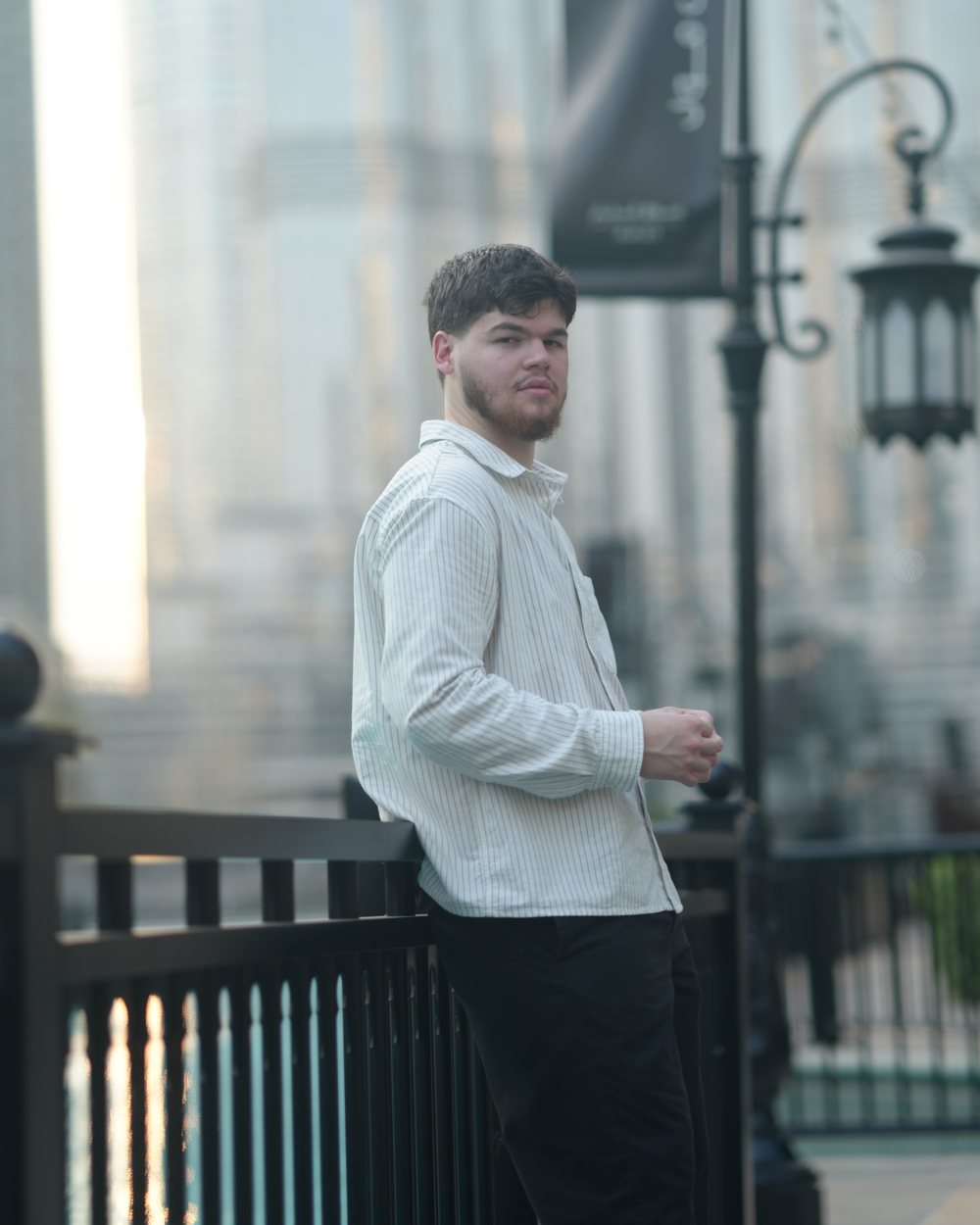 Younes Doughouz in a white striped shirt, leaning on a railing in Downtown Dubai